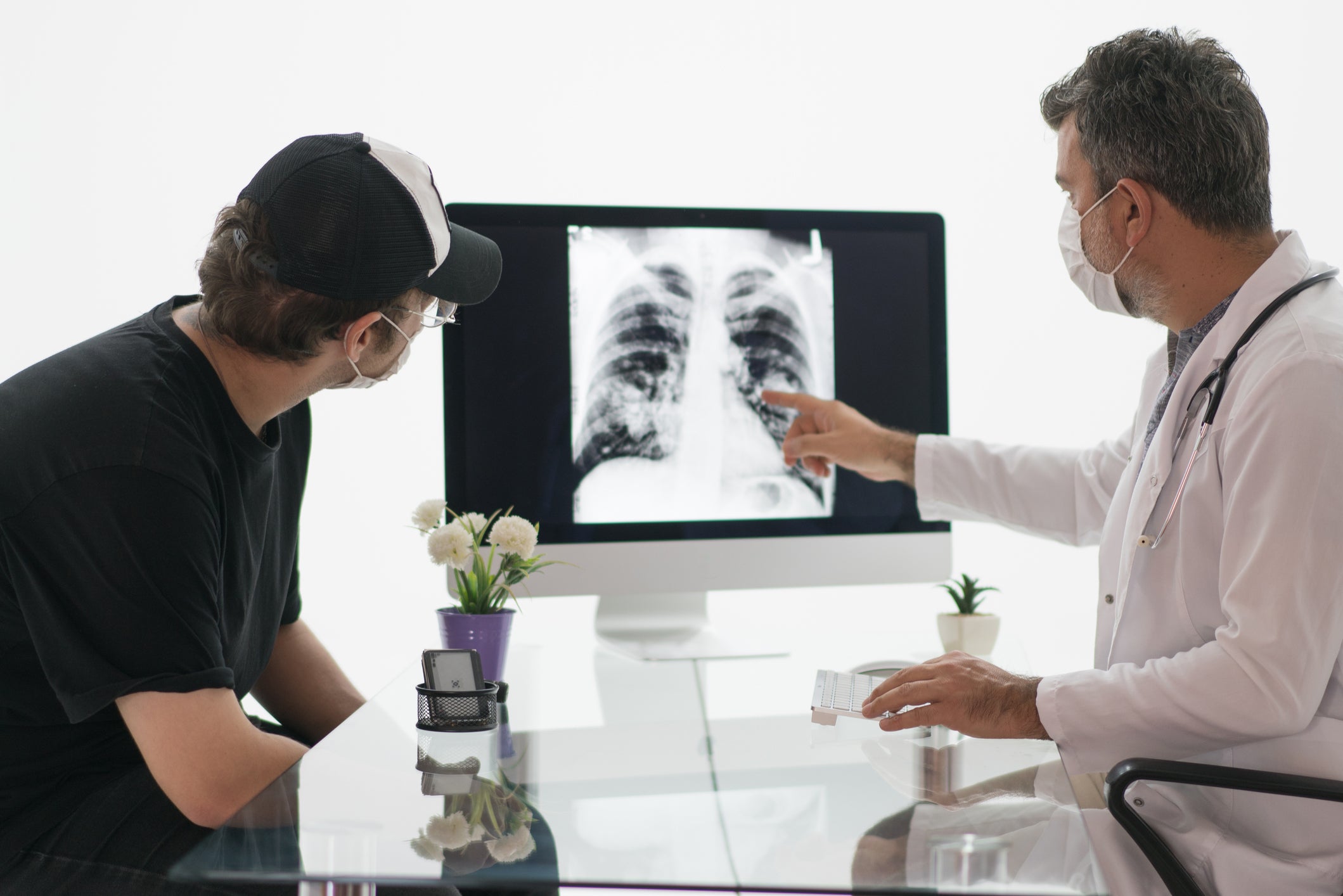 Mature male doctor looks at a radiograph of a chest with his patient.