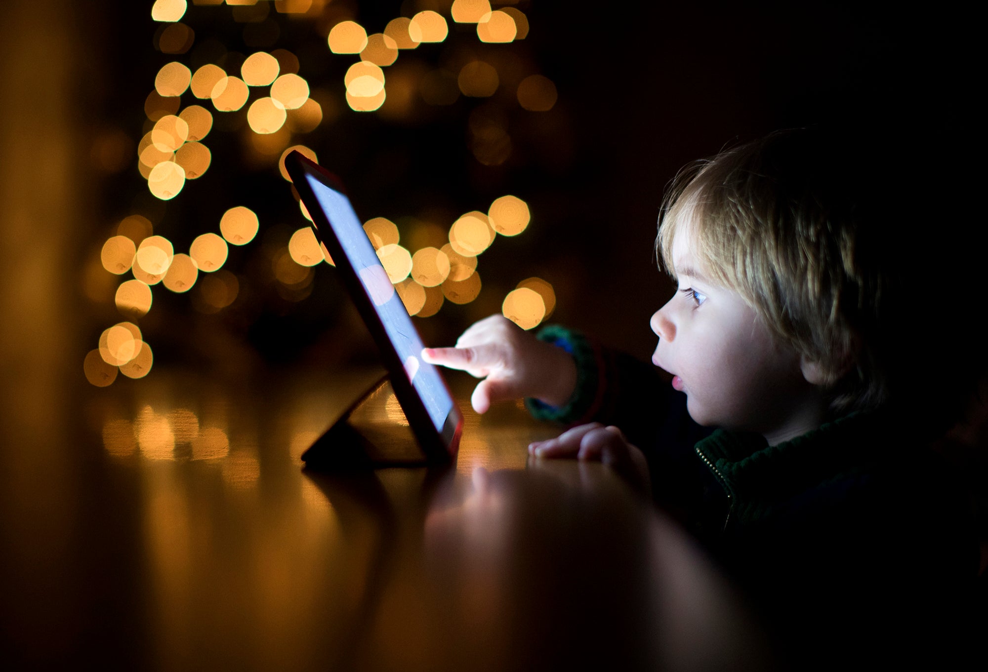 2 year old boy using a digital tablet in the dark