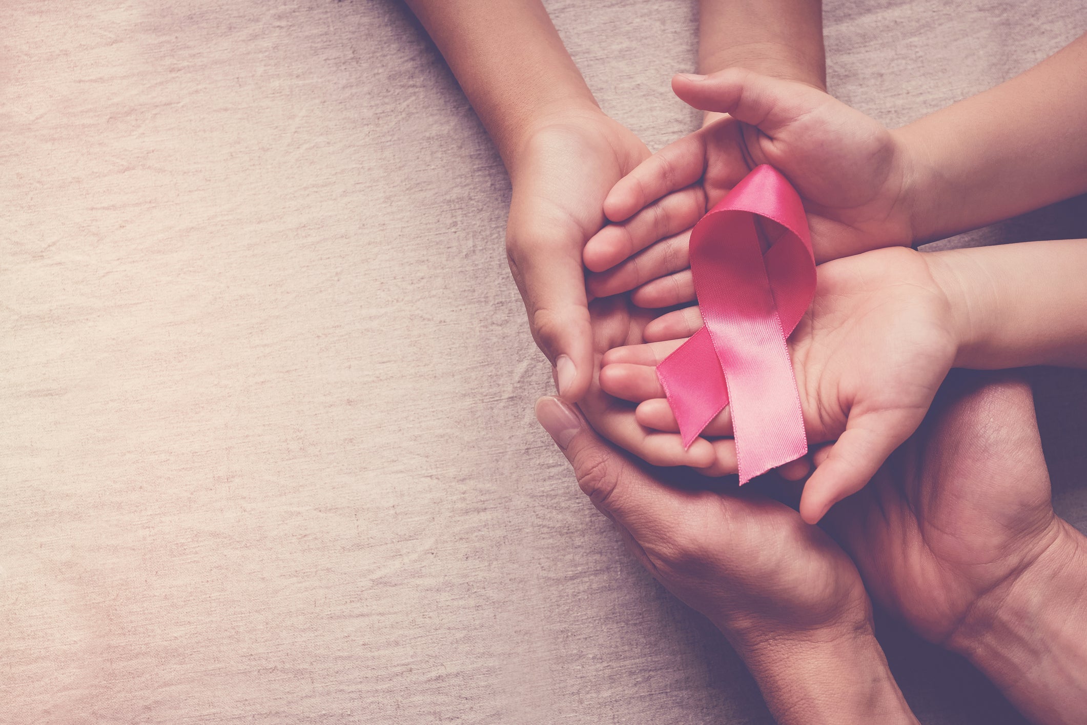 Family hands holding pink ribbon, breast cancer awareness, October pink concept