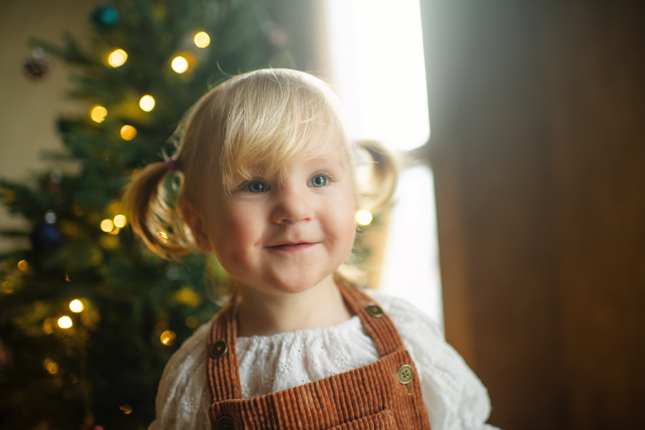Happy little girl  near Christmas tree at home