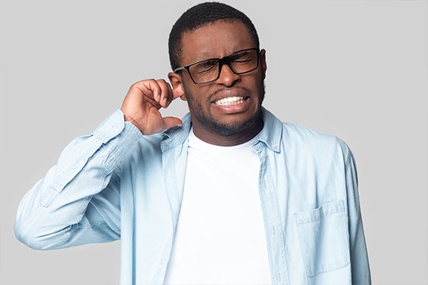 Man with finger in ear wincing.