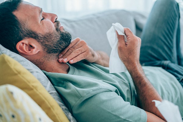 Man laying on couch with sore throat