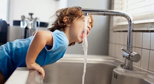 boy drinking from faucet