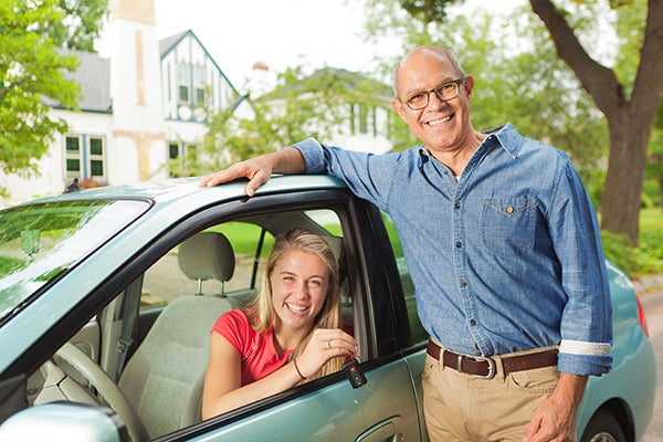 teen in car preparing to drive with dad standing next to the vehicle