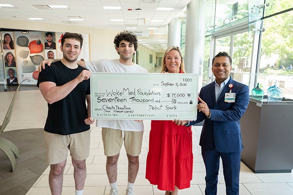 brothers holding check with Ashley and Cancer Care doc
