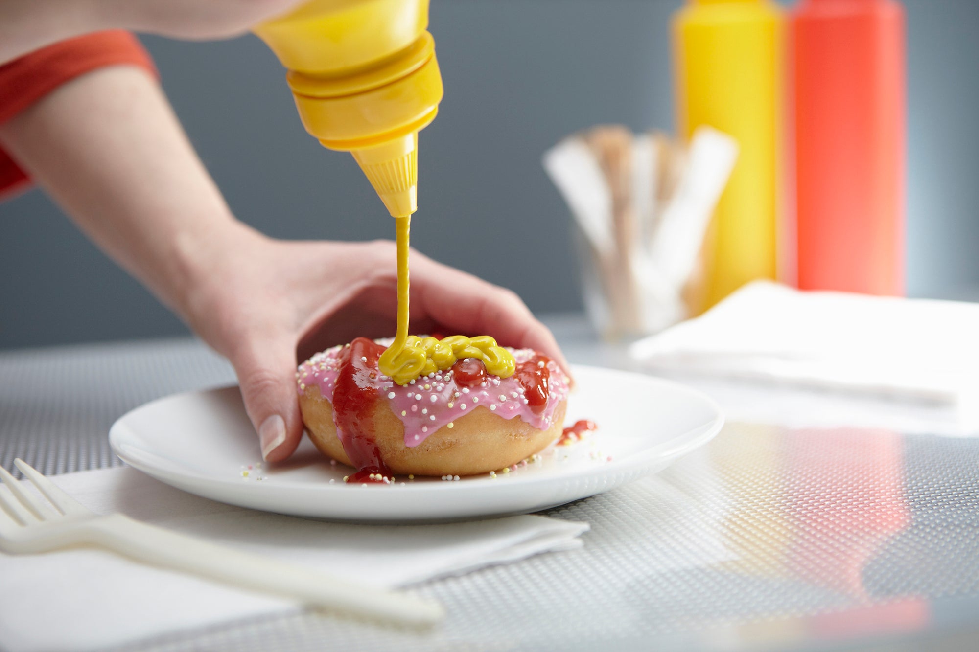 Woman squirting donut with ketchup and mustard