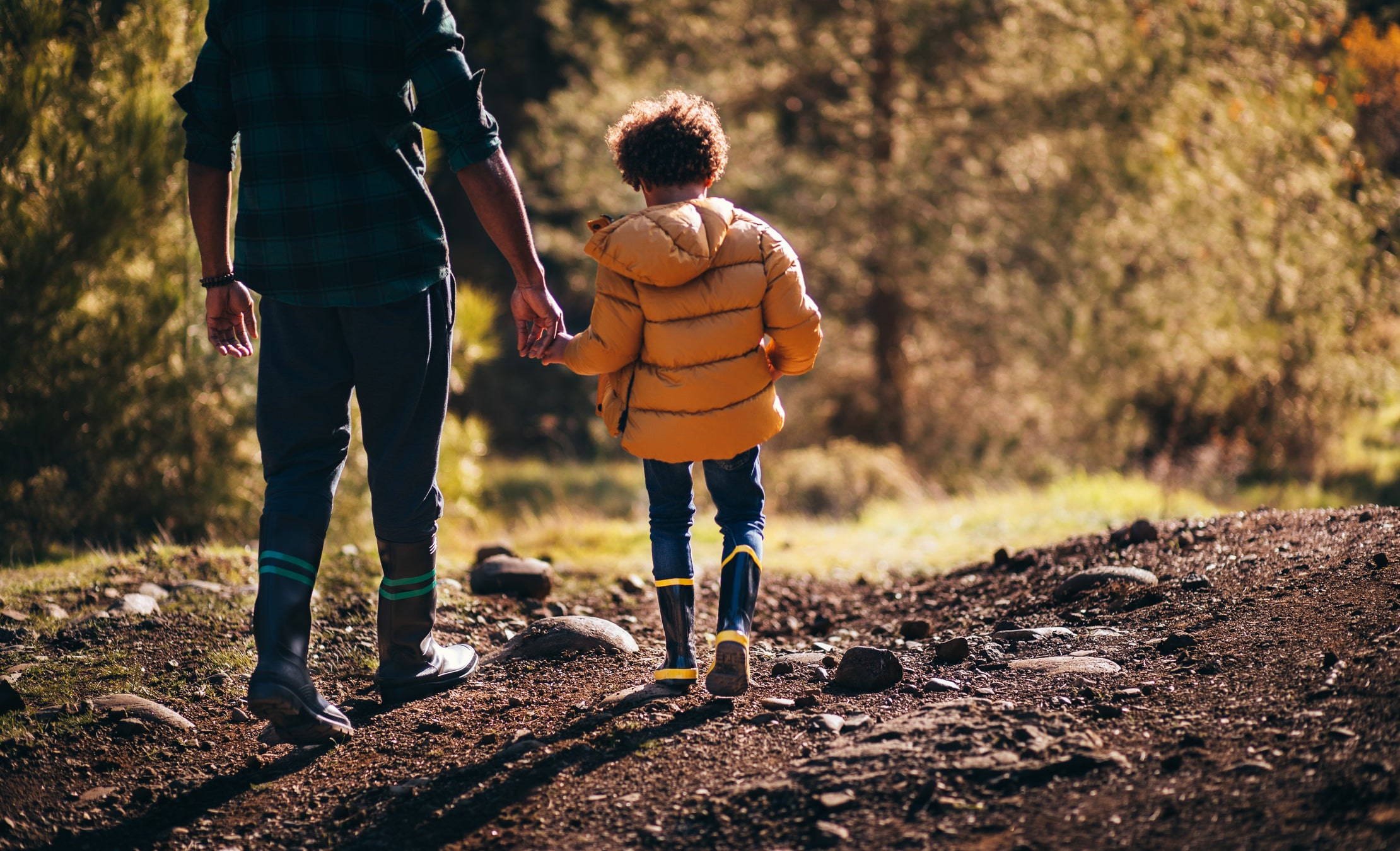 Young father and son with rain boots walking in nature