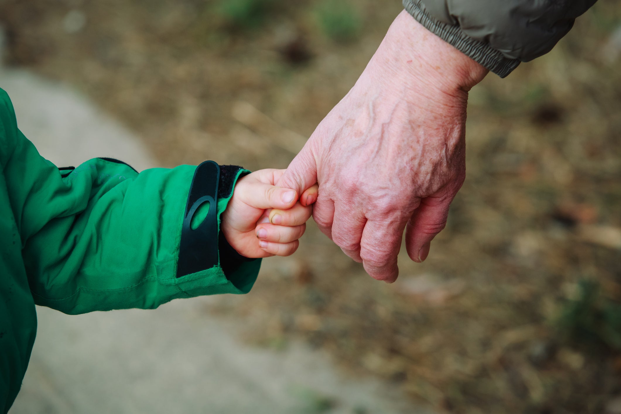 grandmother holding grandchild hand while walk on road