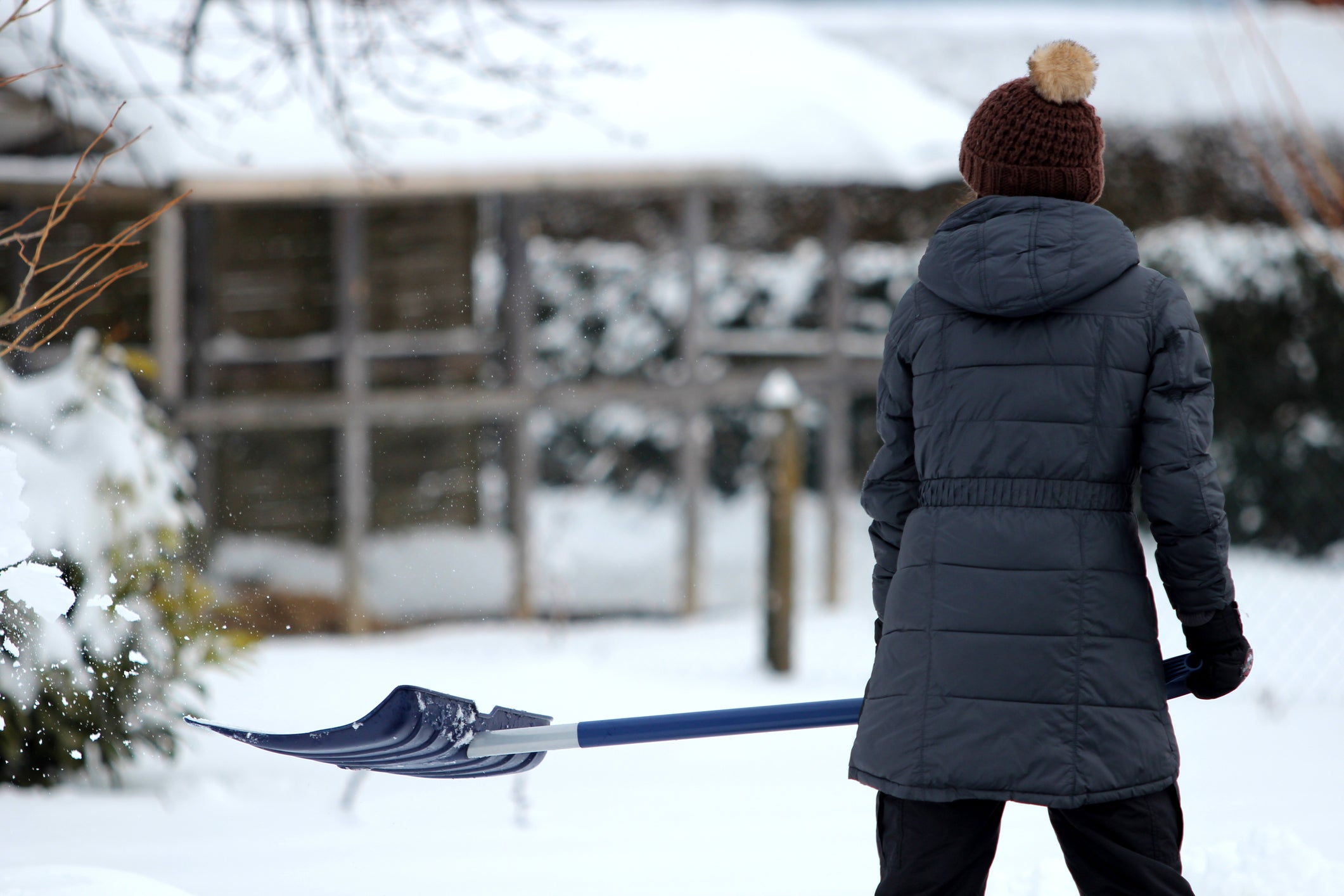 young woman shoveling snow in winter