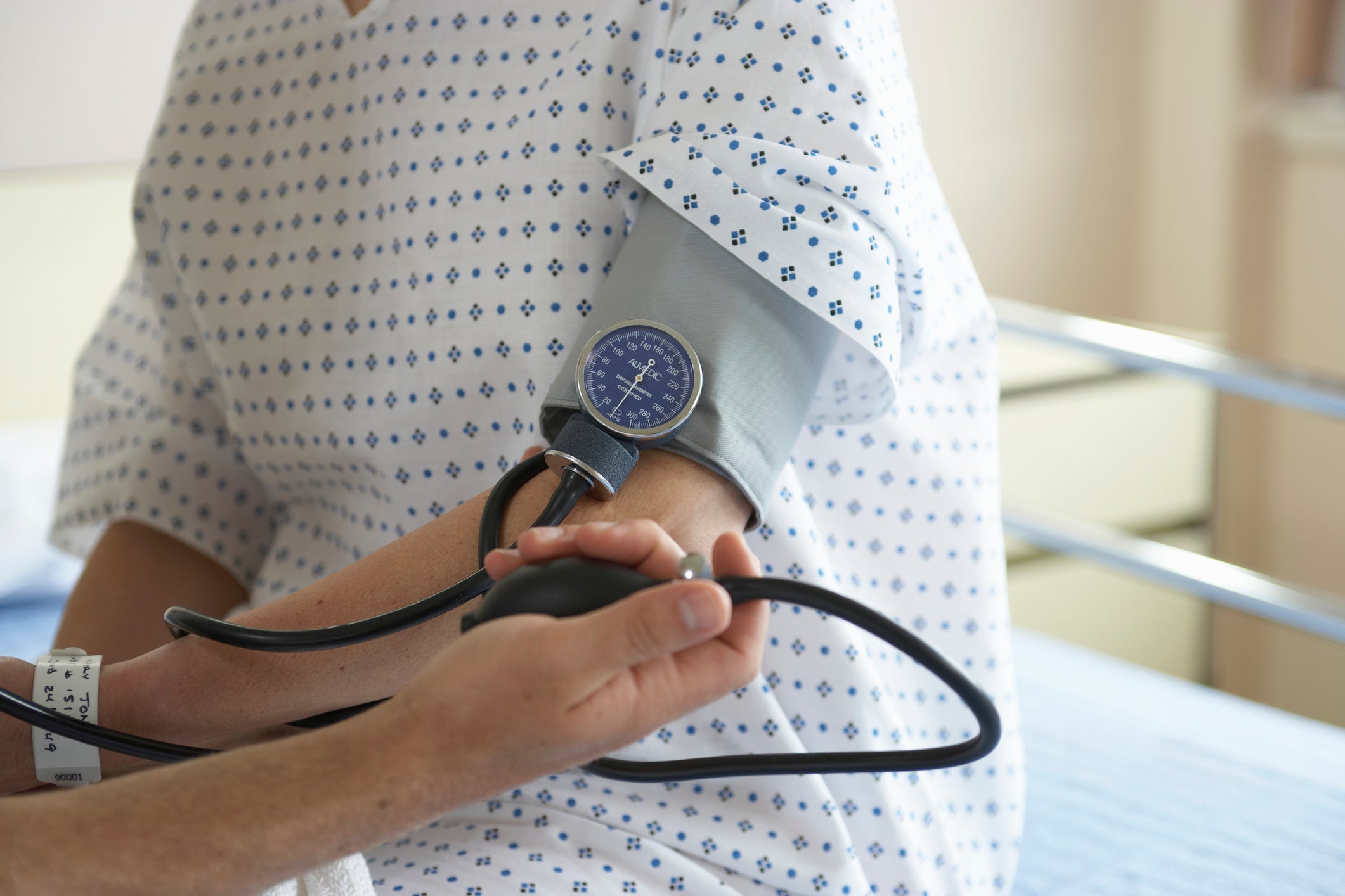 &ldquo;Male doctor checking woman&rsquo;s blood pressure, mid section&rdquo;