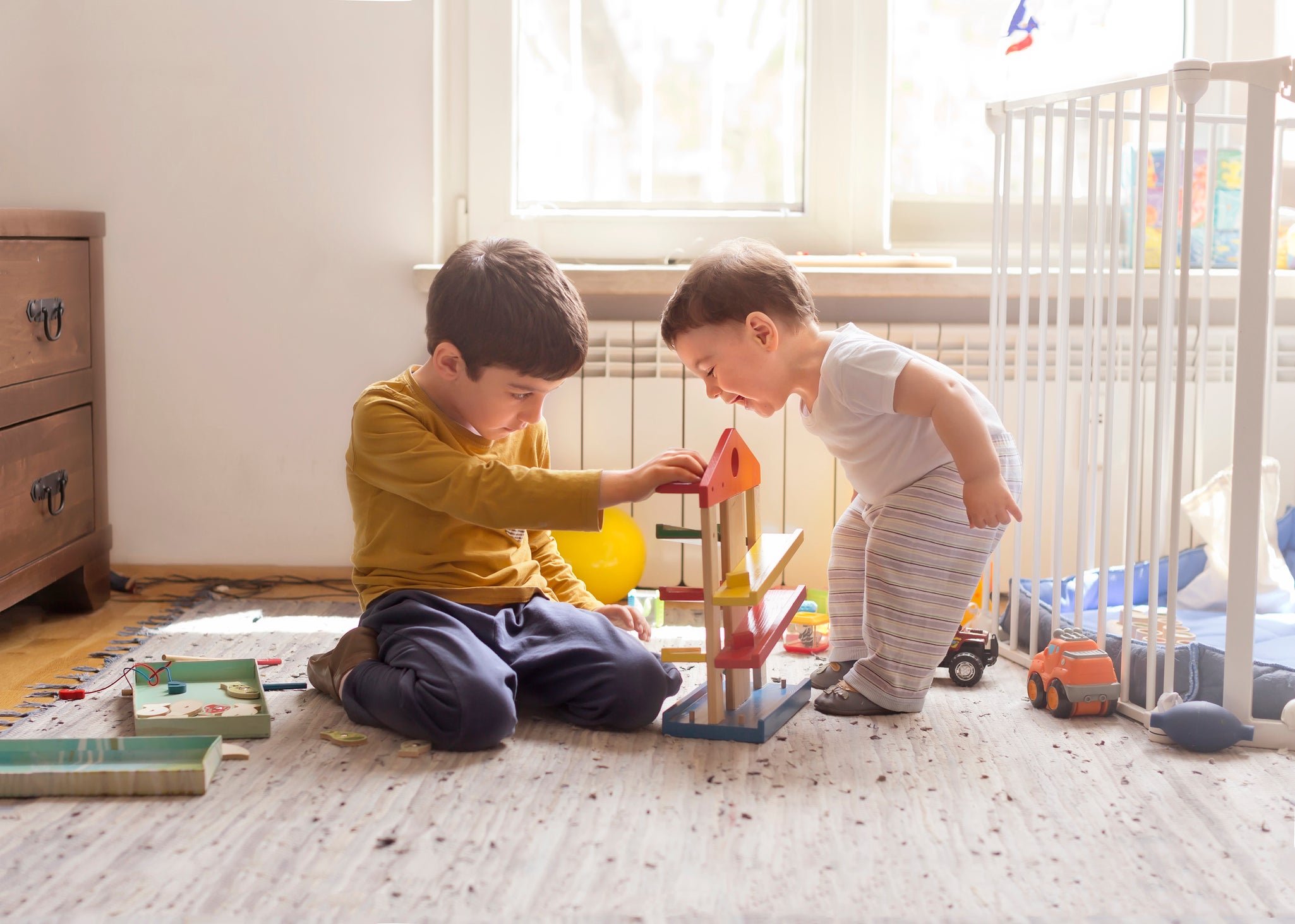 Sibling playing together with wooden toy