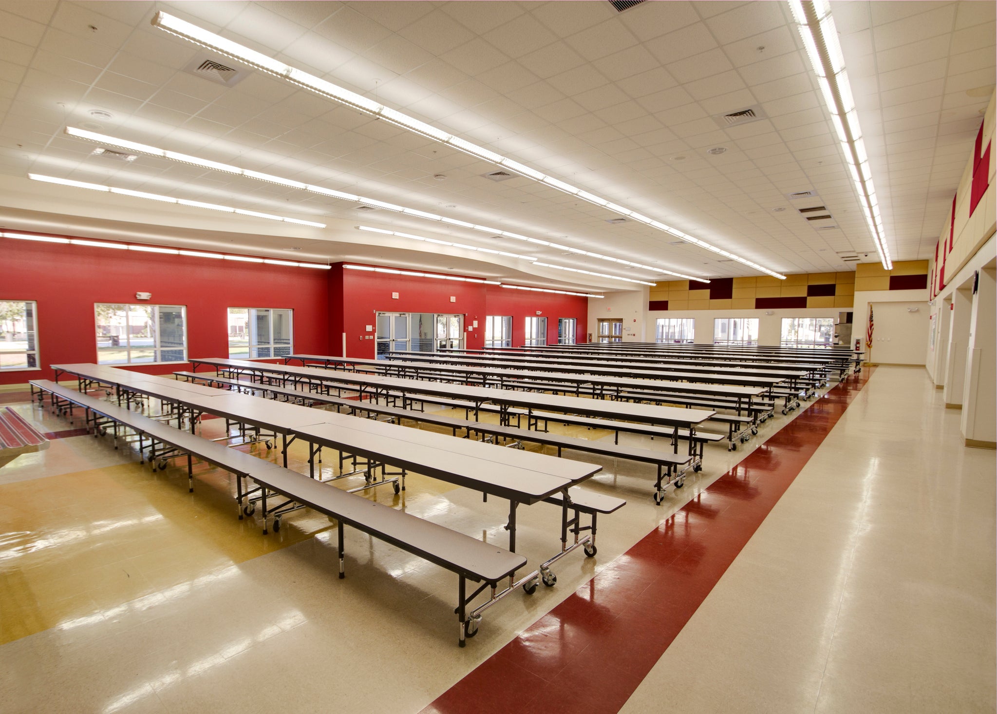 Long tables in an empty red and beige high school cafeteria