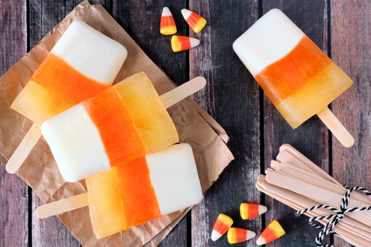Halloween candy corn ice pops on rustic wood background