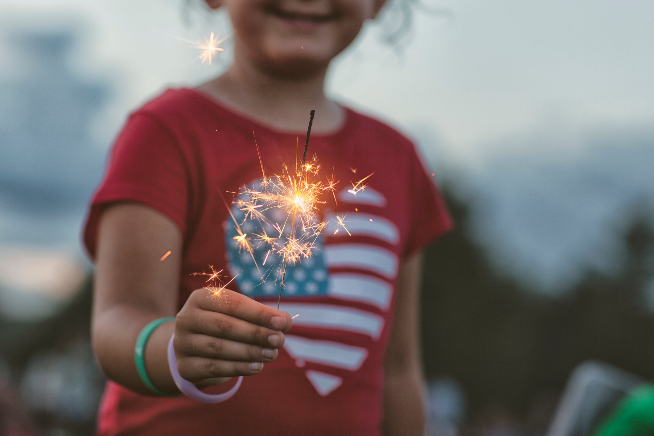 midsection of girl holding lit sparkler