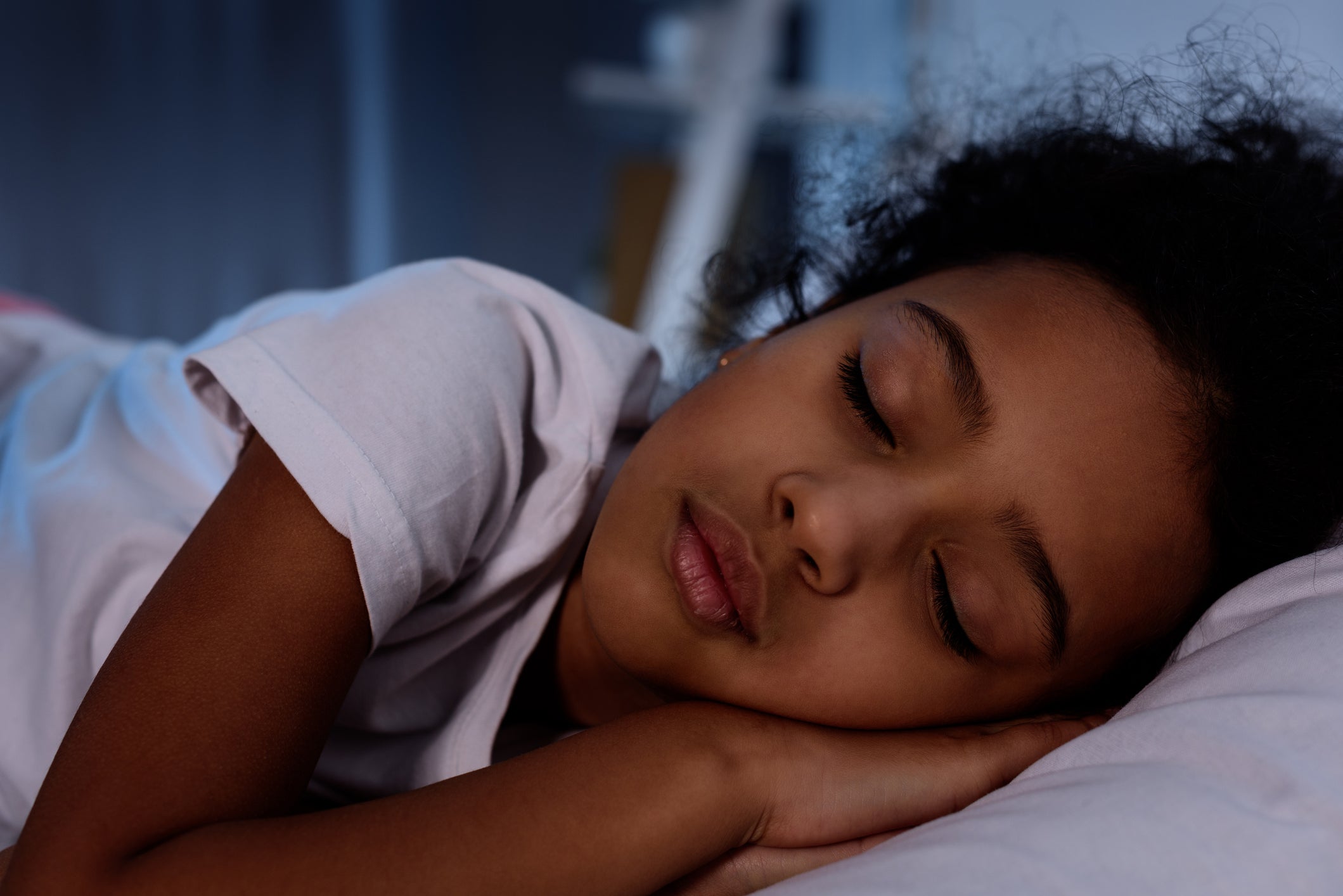 adorable african american kid sleeping in bed at home