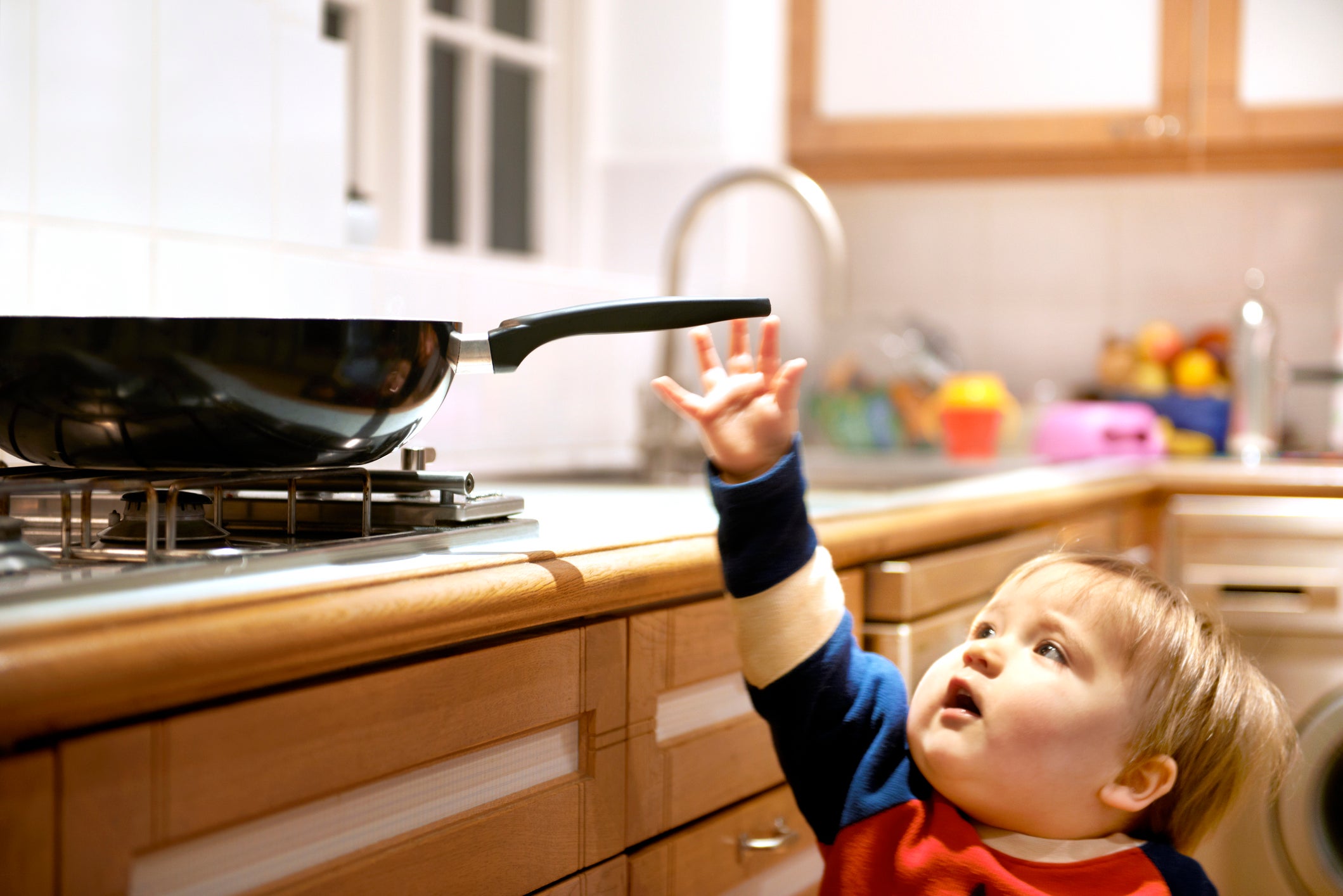 Young boy reaching for a hot pan on a hob