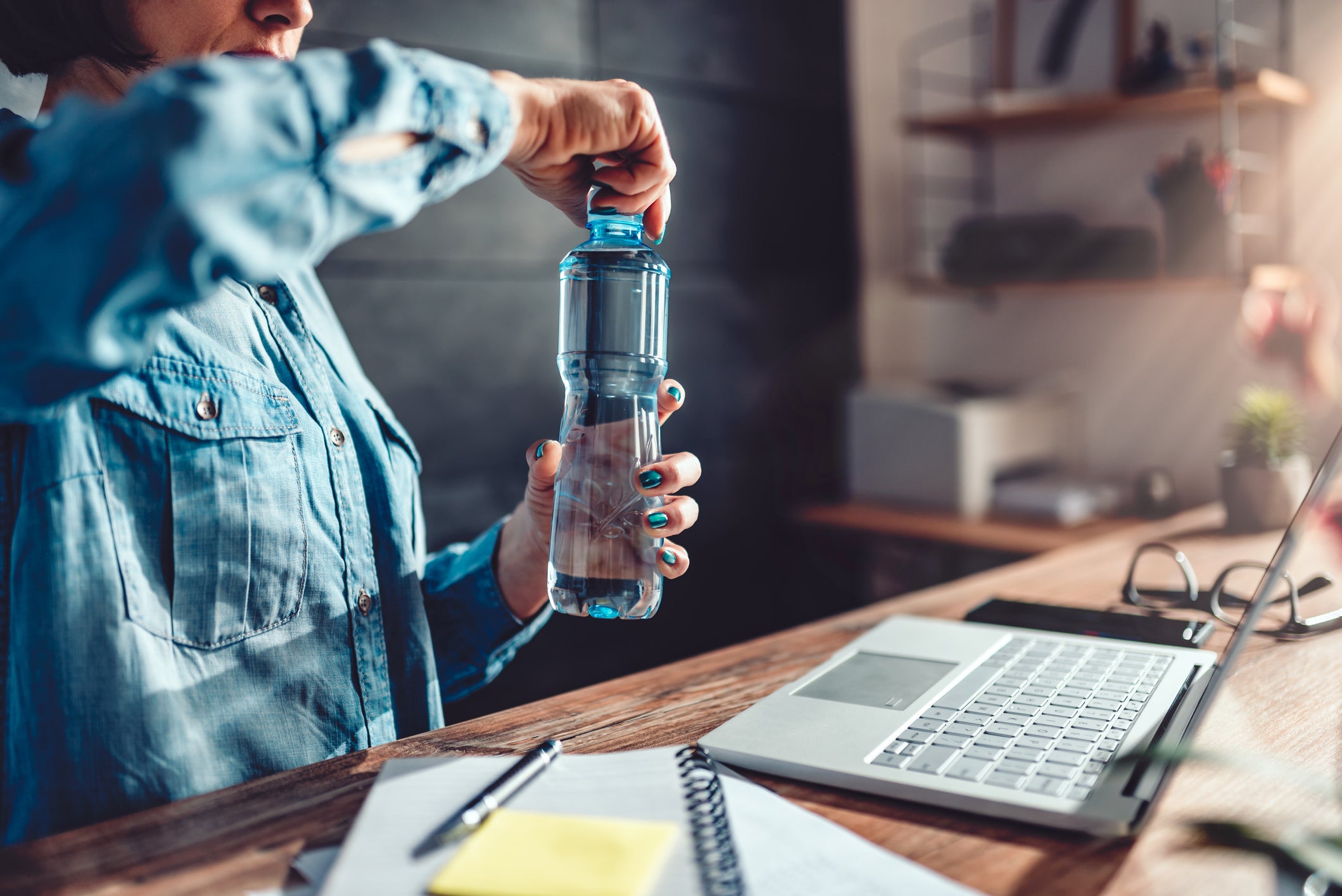 Woman opening bottle of water in the office