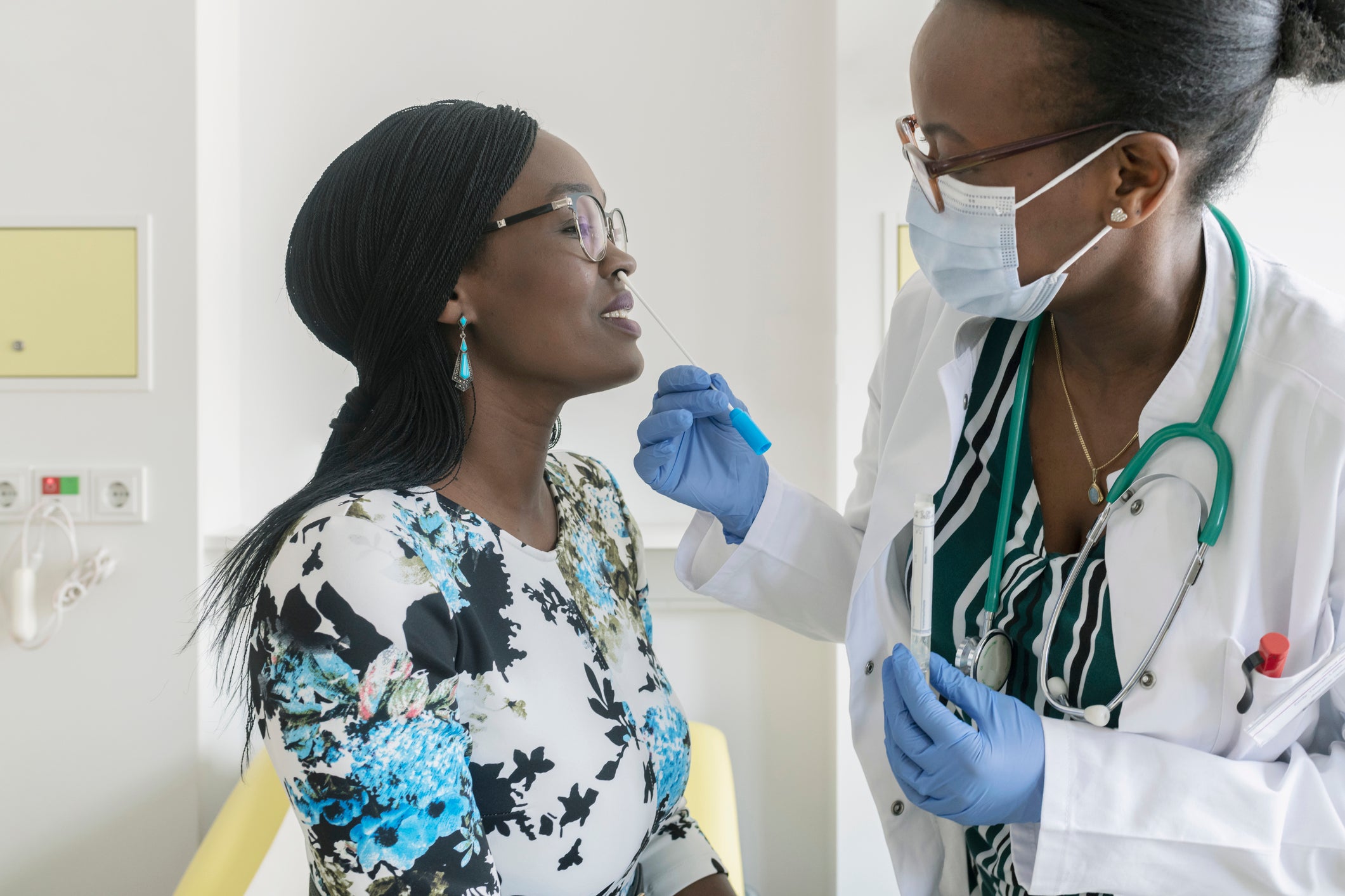 Female doctor taking a nasal swab sample test of mature woman