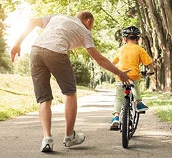 dad teaching child how to ride bike