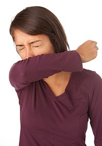 woman coughing into her elbow