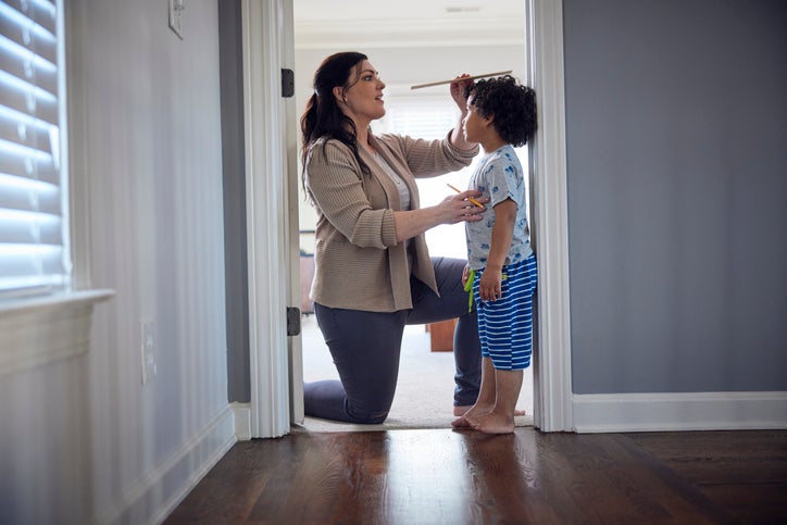 Mom measuring kid's height in the doorway